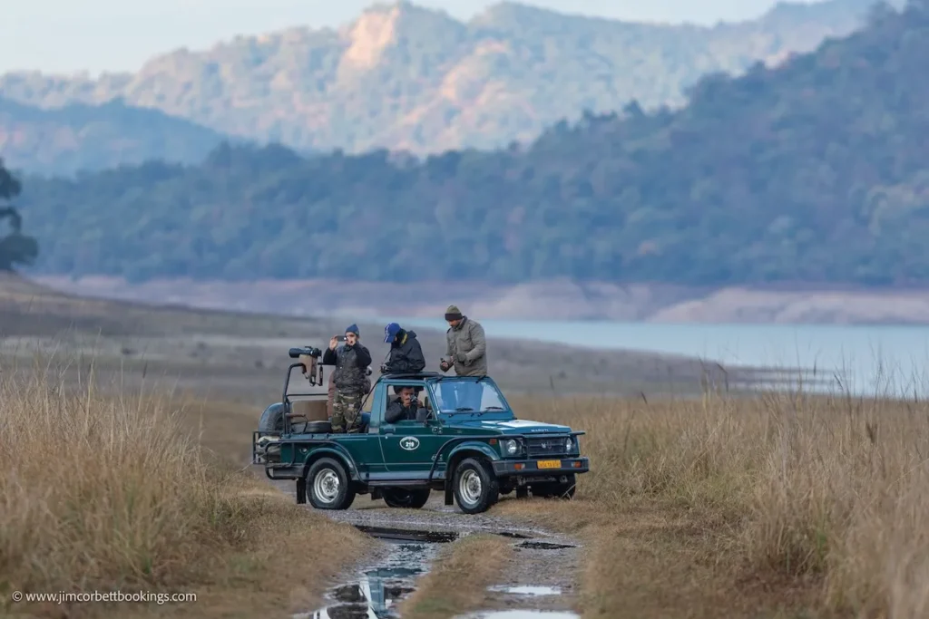Safari jeep with wildlife enthusiasts exploring grasslands near a reservoir, showcasing the value of safari price for nature lovers.