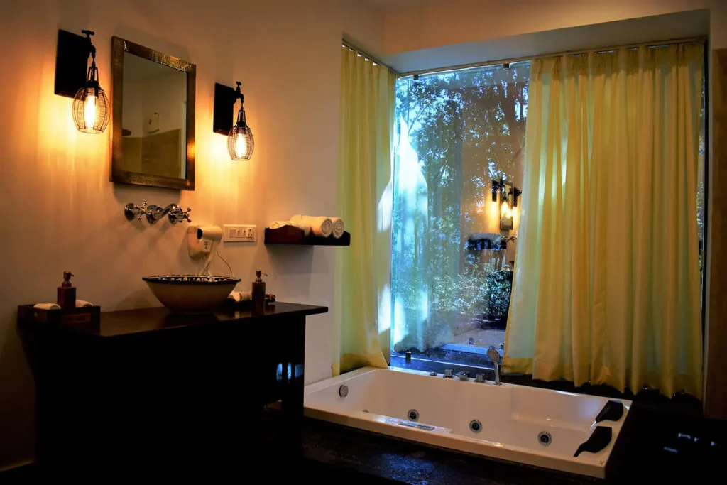 Luxury Resorts in Jim Corbett offering a spacious bathroom with a jacuzzi bathtub, modern amenities, and tranquil forest views.