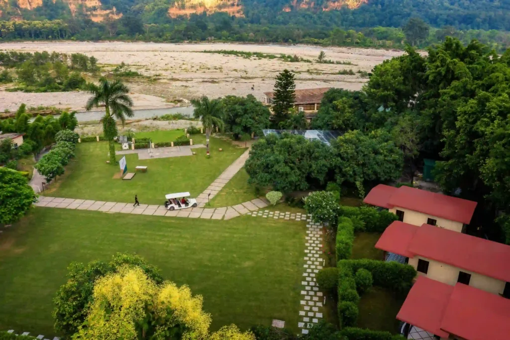 Riverside resorts in Jim Corbett featuring spacious green lawns, comfortable cottages, and a scenic riverfront location ideal for a relaxing wildlife vacation.
